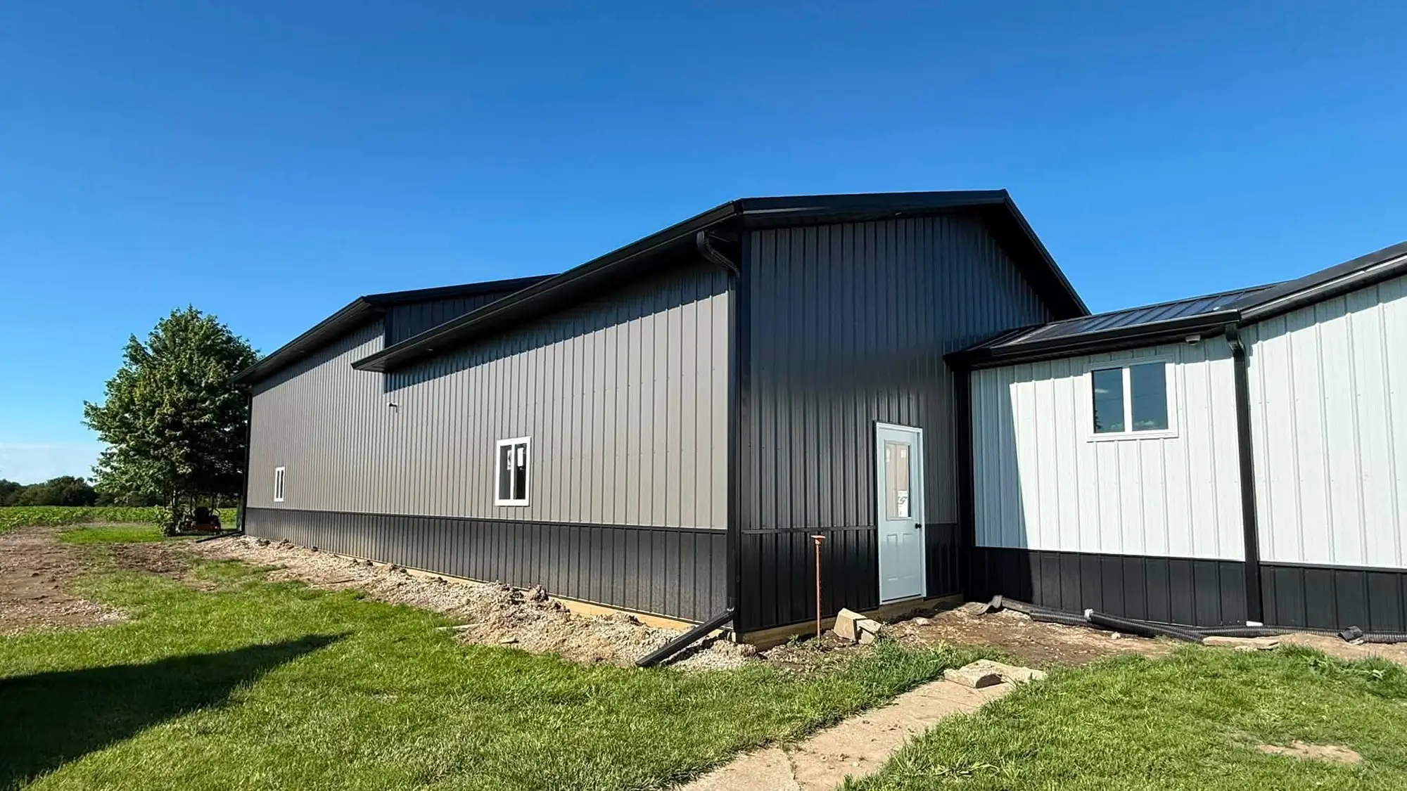 Two connected gray and black shop buildings in southeast Iowa with new black gutters