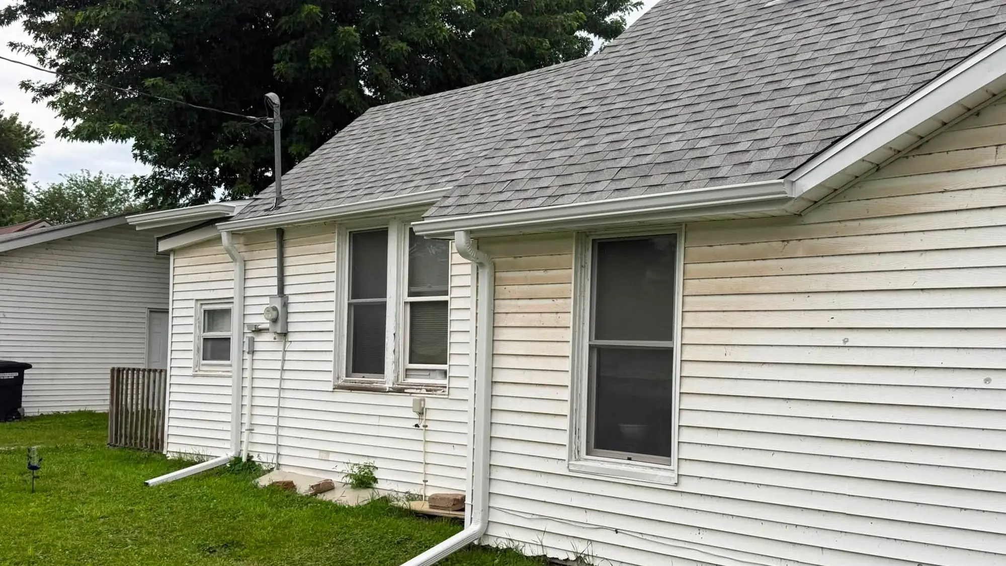 White ranch house with a gray shingle roof and a full-length white seamless gutter
