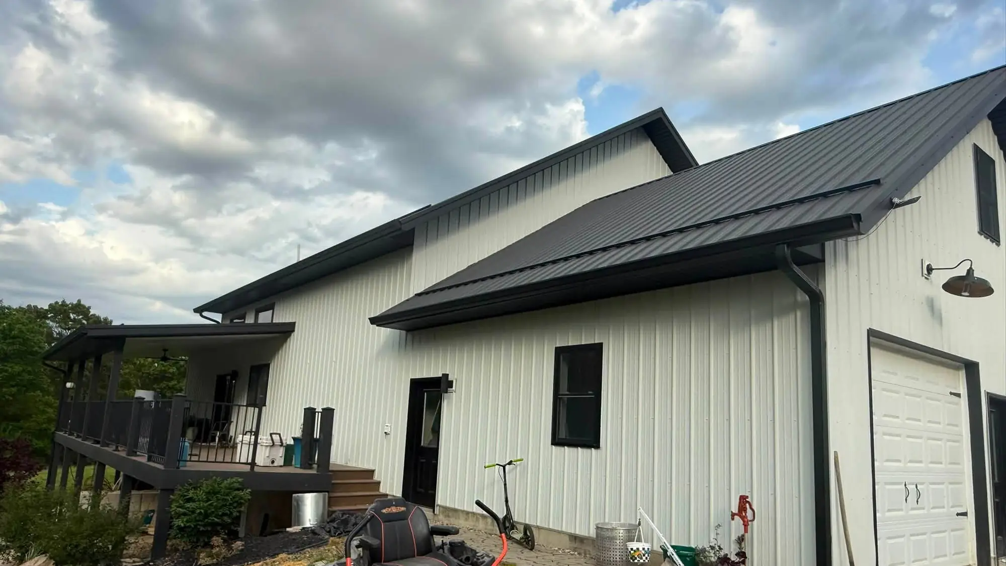 White barndominium with a black standing-seam metal roof and black seamless gutter along the eave