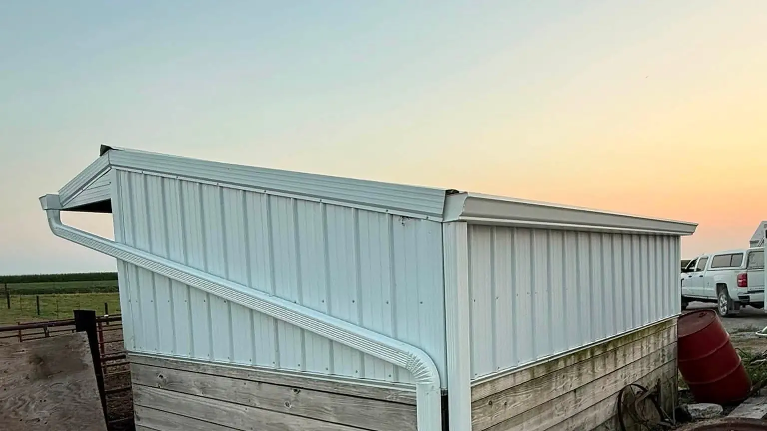 Small white farm shed at sunset in southeast Iowa with a new gutter and downspout