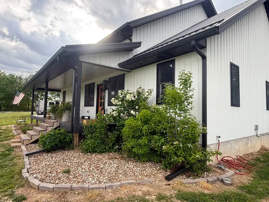 White barndominium with black seamless gutter along the porch roof