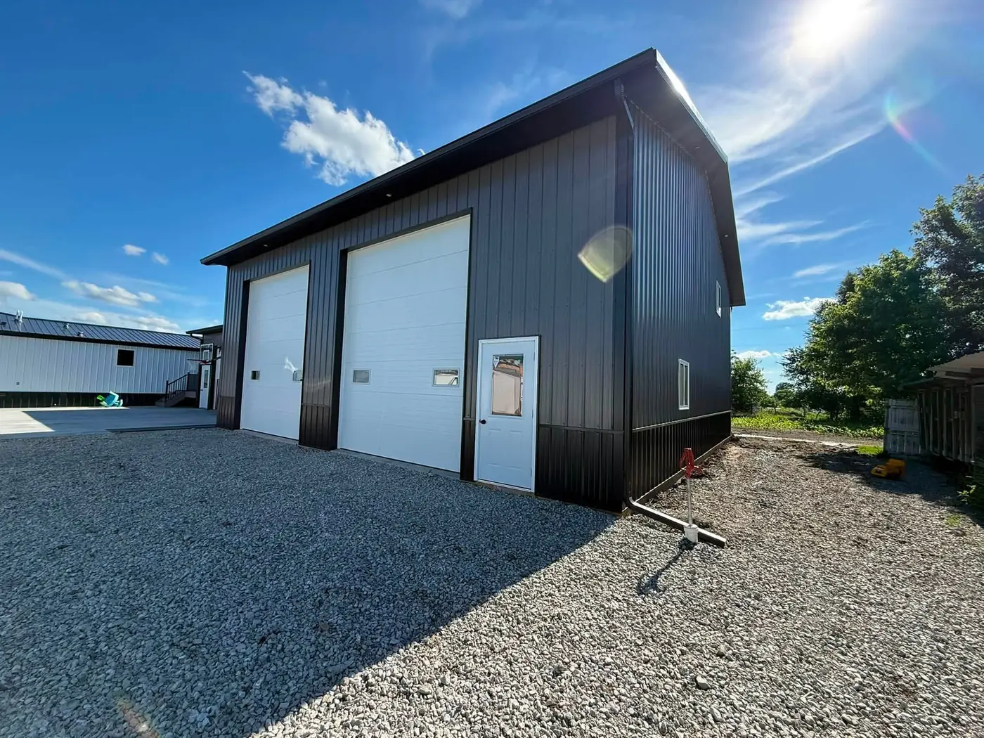 Black pole building with new gutter over two overhead doors