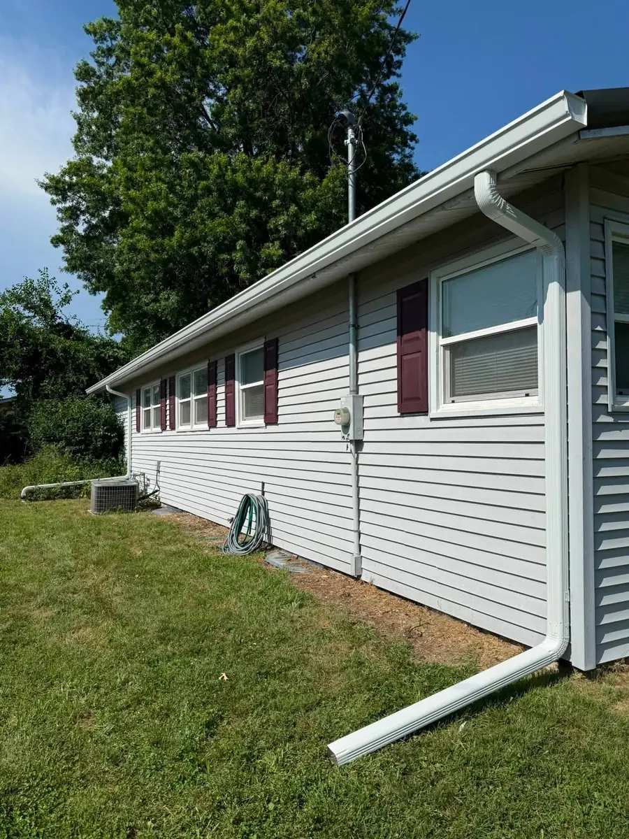 Gray ranch house with a white downspout and long ground extension