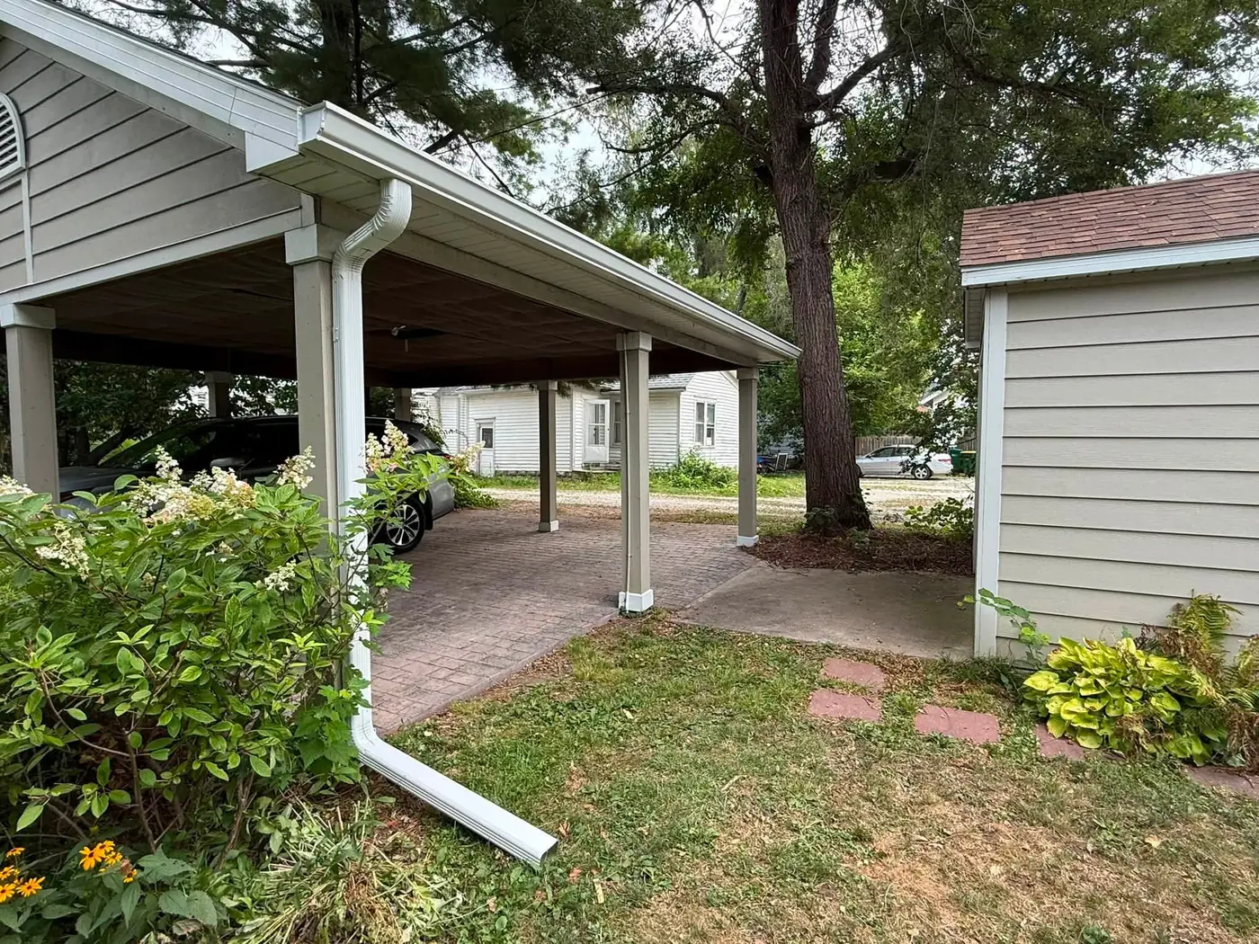 White carport and breezeway between a house and garage with gutter on both slopes