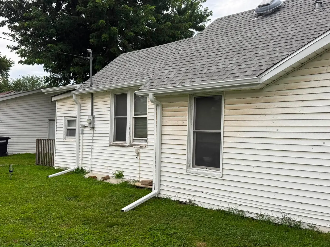 White ranch house with a gray shingle roof and a white gutter with two downspouts